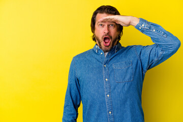 Middle age caucasian man isolated on yellow background shouts loud, keeps eyes opened and hands...