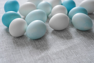 White and blue Easter eggs on grey linen cloth. Soft light soft colors. Close up
