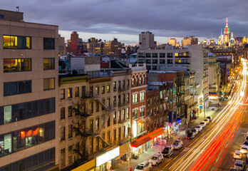 Fototapeta na wymiar New York City busy overhead street view of Bowery through Chinatown with car lights streaking down the road from long exposure at night