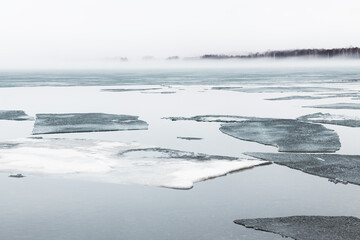 Fototapeta na wymiar Melting ice on the shore of lake in misty morning. Beautiful spring landscape.
