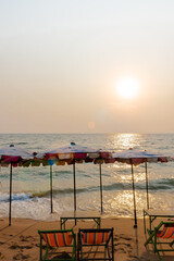 Beautiful Summer beach with sun umbrellas and beach chairs, Sun above the sea with lens flare effect