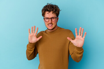 Young caucasian man wearing eyeglasses isolated on blue background rejecting someone showing a...