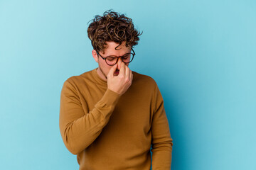 Fototapeta na wymiar Young caucasian man wearing eyeglasses isolated on blue background having a head ache, touching front of the face.