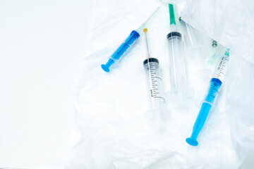 Several disposable syringes of different sizes close-up on a white surface. Selective focus. Medical equipment for intravenous and intramuscular injection of medicinal solutions.