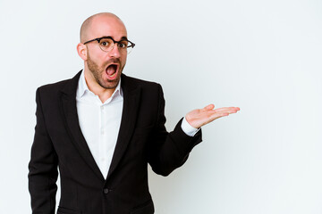 Young business caucasian bald man isolated on white background impressed holding copy space on palm.
