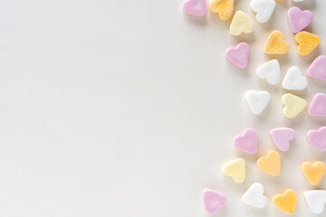 Flat lay of heart shaped colourful candy on white background with copy space, sweets in pink, white, yellow, orange, pink pastels colours