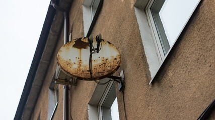 black satellite dish attached to brick wall (residential house, copy-space available)