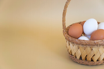 White and brown eggs in wicker basket on pastel beige background. Fresh farm chicken eggs. Happy Easter with copy space.