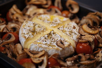 Camembert baked.Cheese with mushrooms and tomatoes in a baking sheet.Baked Camembert cheese with vegetables