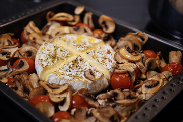 Camembert baked.Cheese with mushrooms and tomatoes in a baking sheet.Baked Camembert cheese with...