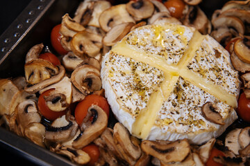 Camembert baked.Cheese with mushrooms and tomatoes in a baking sheet.Baked Camembert cheese with vegetables