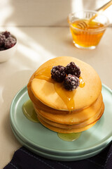 Pancakes on turquoise plate with honey and blackberries. Breakfast. Meal.
