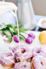 Homemade Purple donuts on dessert stand with Spring flowers