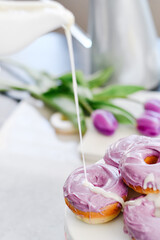 Homemade Purple donuts on dessert stand with Spring flowers