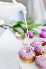 Homemade Purple donuts on dessert stand with Spring flowers