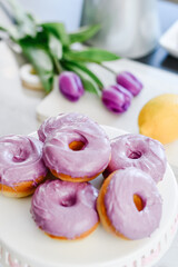 Homemade Purple donuts on dessert stand with Spring flowers