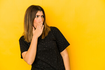Young indian woman isolated on yellow background being shocked because of something she has seen.