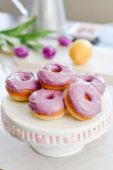 Homemade Purple donuts on dessert stand with Spring flowers