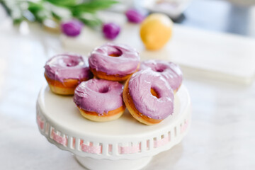 Homemade Purple donuts on dessert stand with Spring flowers