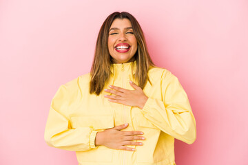 Young indian woman isolated on pink background laughs happily and has fun keeping hands on stomach.