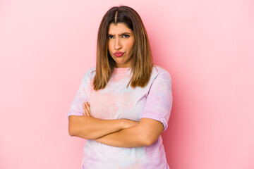 Young indian woman isolated on pink background frowning face in displeasure, keeps arms folded.