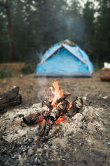 Bonfire on the background of a blue tent in the early morning