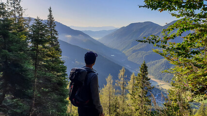A man with a hiking backpack enjoying the view on the Alpine valley from the way to Hohe Weichsel...