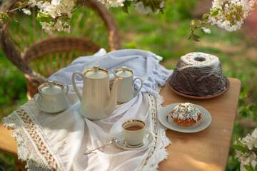 Coffee set on a white tablecloth on a sunny day, cherry blossom, cupcake, pudding. Outdoor, picnic, brunch, spring mood. Soft focus