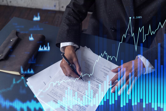 African American businesswoman in formal wear is signing the contract to invest money in stock market. Internet trading and wealth management. Forex and financial hologram chart.