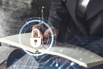 Businesswoman is taking notes of clients needs to protect cyber security from hacker attacks and save clients confidential data. Padlock Hologram icons over the typing hands. Formal wear