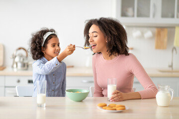 Afro Girl Feeding Young Woman With Cereal