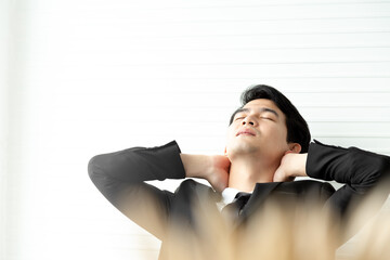 Portrait exhausted businessman in black suite disappointed or failing at the office. He try relaxing with hands behind head. Having break at office concept.