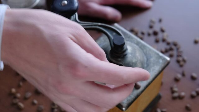 A man pours coffee beans into a coffee grinder, closeup