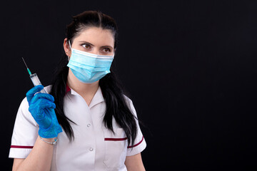 doctor in mask holding a syringe, closeup, vaccination and immunization concept, isolated on dark