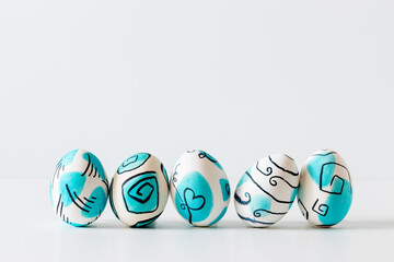 Creative trendy painted easter eggs on white background.
