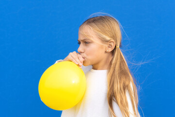 Close up photo of nice pretty lovely girl inflate ballon have free time positive cheerful funny girl isolated on blue colorful background. High quality photo