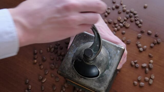 Man grinds coffee beans in a manual vintage coffee grinder, close-up