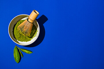 Matches tea and whisk on a blue background. Fresh tea leaves and everything for making a tea drink. Super drink, Chinese tea for health. Top view. Copy space. 