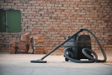 Industrial vacuum cleaner on the dusty floor of construction site.