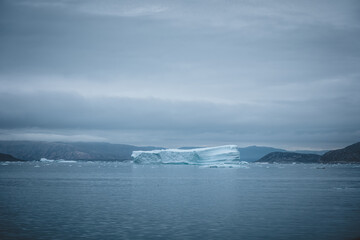 Arctic nature landscape with icebergs in Greenland icefjord with midnight sun sunset sunrise in the horizon. Early morning summer alpenglow during midnight season. Ilulissat, West Greenland.