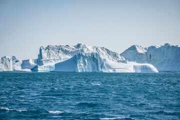 Fototapeta na wymiar Bright sunny day in Antarctica. Full calm and reflection of icebergs in deep clear water. Travel by the ship among ices. Snow and ices of the Antarctic islands.