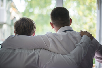 Two male friends embracing and looking out the window