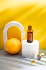 Glass cosmetic bottle with oil or serum for skin care on special podium on yellow background. Shadows Natural skin care concept. Harsh shadows