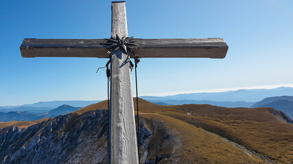 A wooden cross on top of Hohe Weichsel, Alpine peak in Austria. The cross is leaning, as if it was...