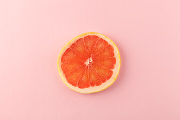 A slice of pink grapefruit against a pink background.