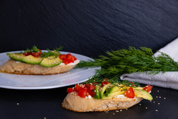 slices of avocado and slices of tomato are laid out on a piece of baguette