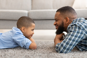 African Father And Son Lying On Floor At Home, Side-View