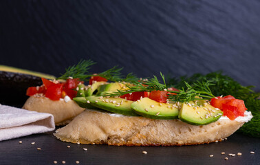 delicious canapes, slices of fresh avocado and slices of ripe tomato are laid out on a piece of baguette