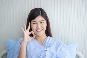 Female patient, beautiful smile, Asian Sitting in a hospital bed, thumbs up. Okay. The concept of medical services, health insurance.