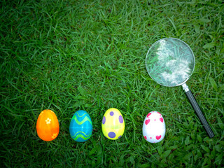 Colorful Easter eggs on green grass with magnifying glass, Easter egg hunter